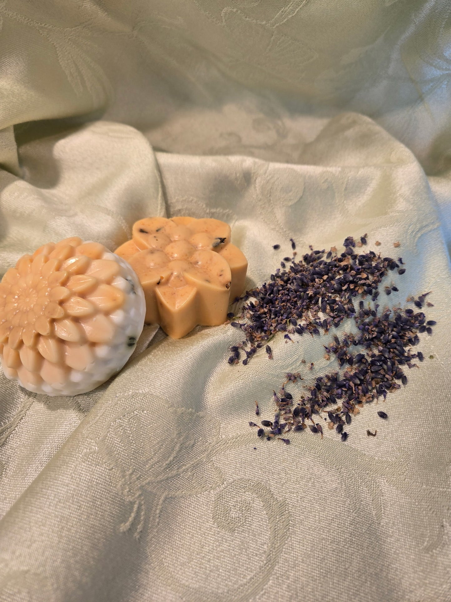 Three soaps with different designs on a textured fabric surface with dried lavender.