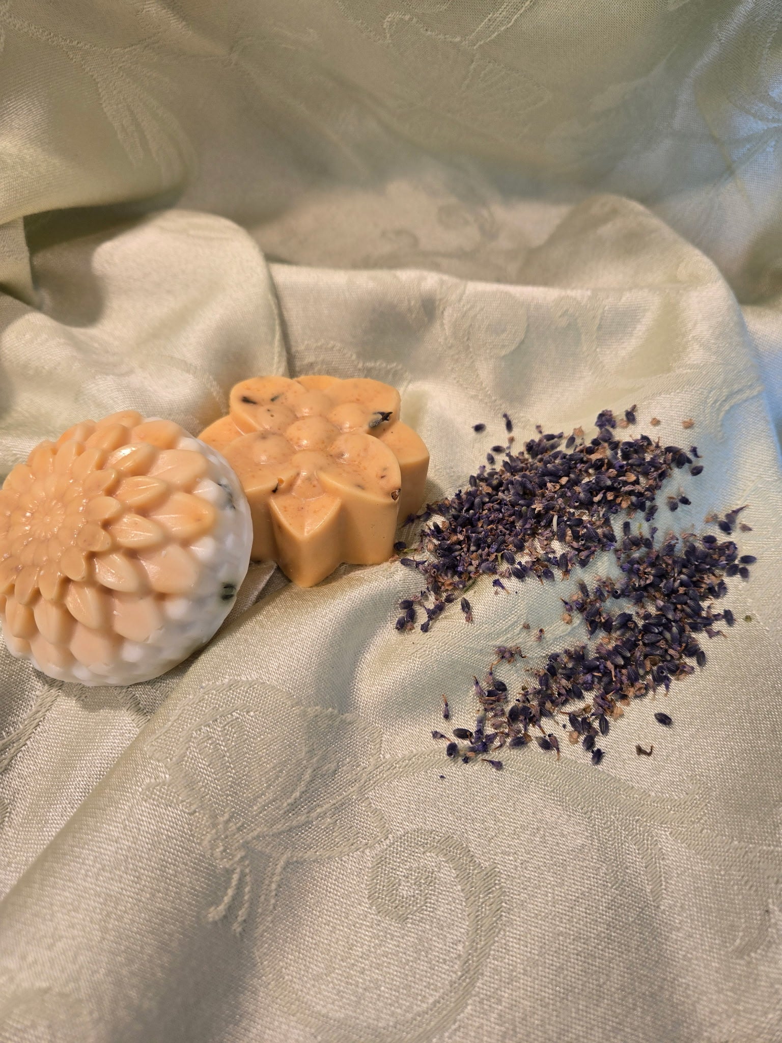 Three soaps with different designs on a textured fabric surface with dried lavender.