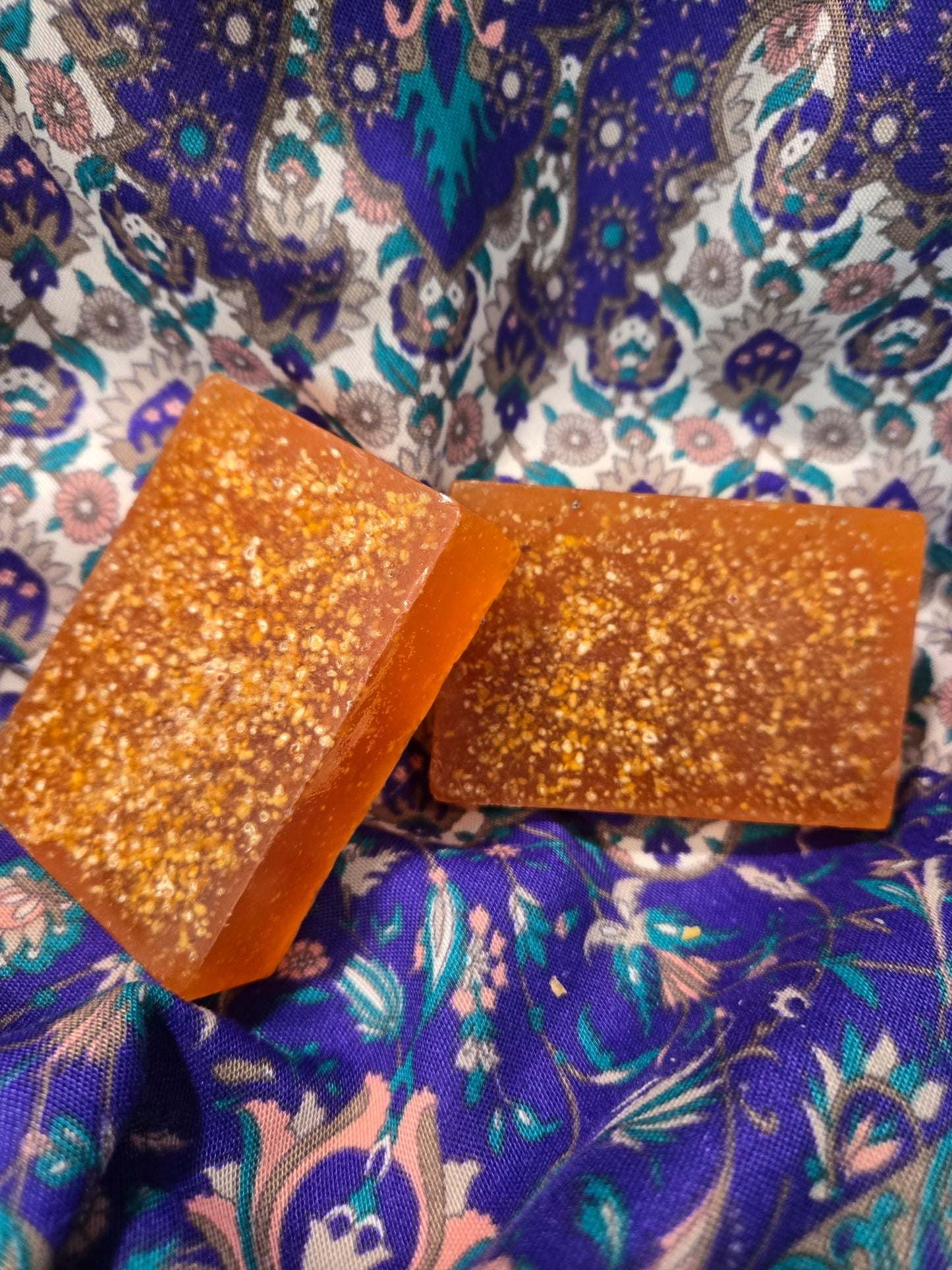Two orange glittery blocks of soap on a patterned background