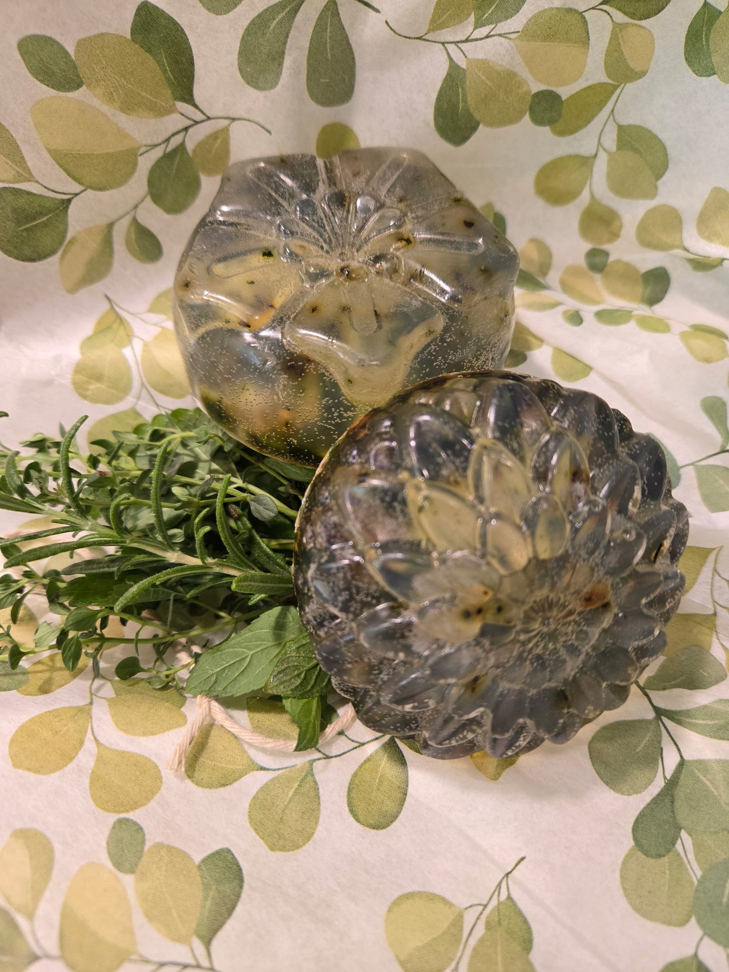 Two decorative clear soaps on a leaf-patterned fabric background